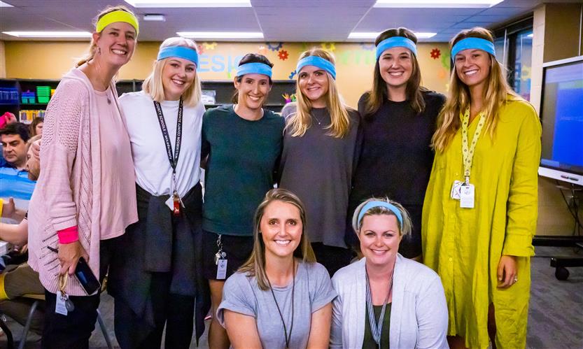 Teachers pose while wearing neon sweatbands
